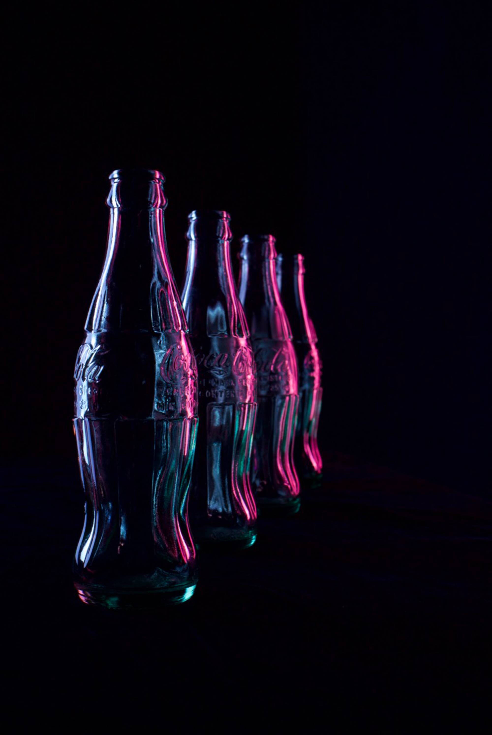 Dark photograph of glass bottles with a pink light.